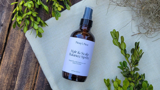 Nessys' Nest bottle of Hair & Scalp Balance Spritz on linen and wood surface with greenery.